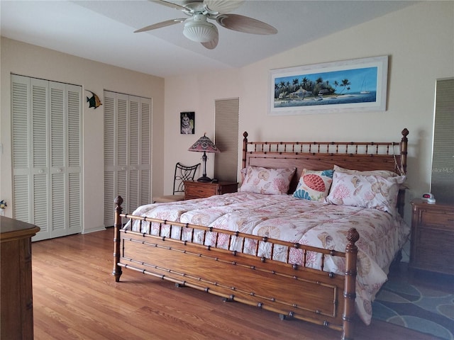 bedroom featuring vaulted ceiling, ceiling fan, two closets, and wood-type flooring