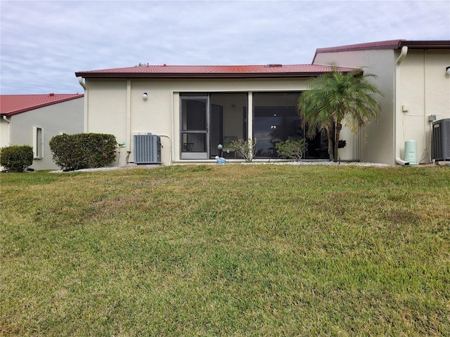 rear view of house featuring central air condition unit, a lawn, and a sunroom