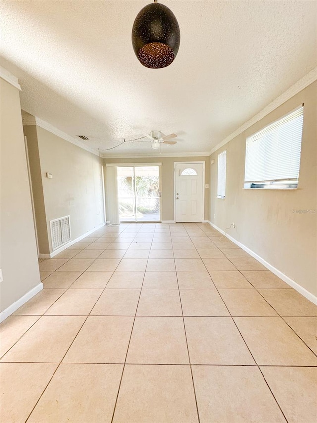 empty room featuring crown molding, light tile patterned flooring, a textured ceiling, and ceiling fan