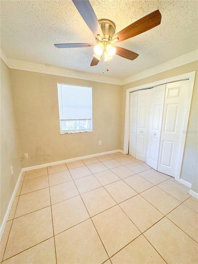 unfurnished bedroom featuring a closet, ceiling fan, crown molding, and light tile patterned flooring