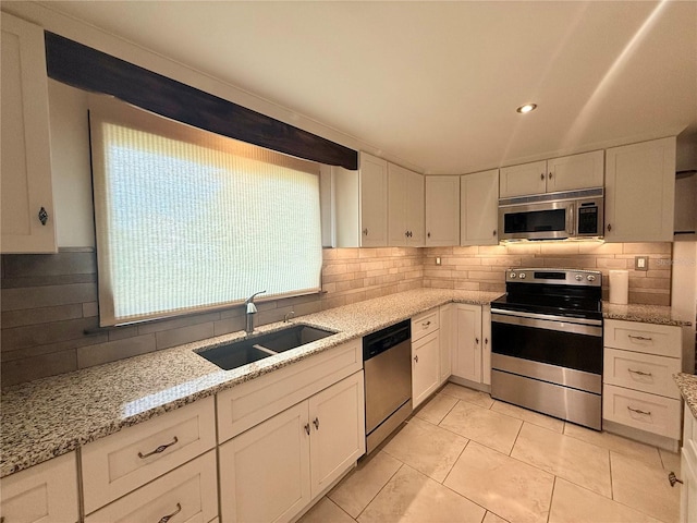 kitchen with light stone countertops, white cabinets, stainless steel appliances, tasteful backsplash, and sink