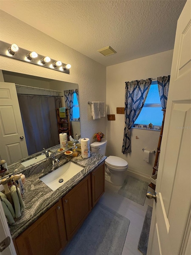 bathroom featuring a textured ceiling, toilet, and vanity