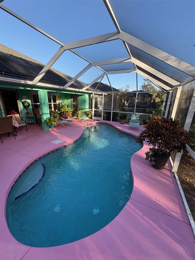 view of swimming pool featuring glass enclosure and a patio