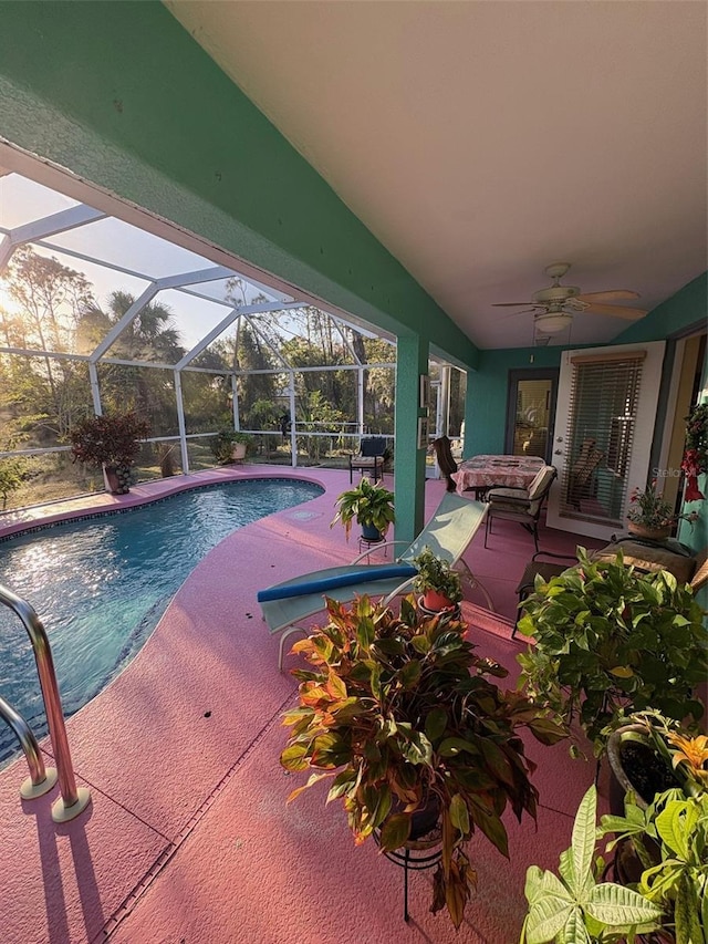 view of swimming pool with glass enclosure, ceiling fan, and a patio area