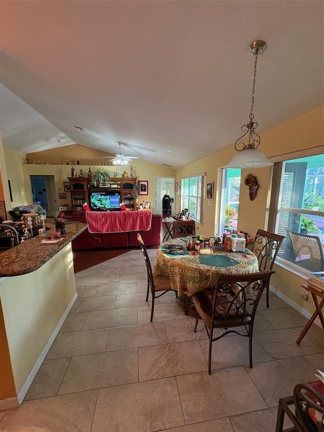 dining space featuring ceiling fan, light tile patterned floors, and vaulted ceiling