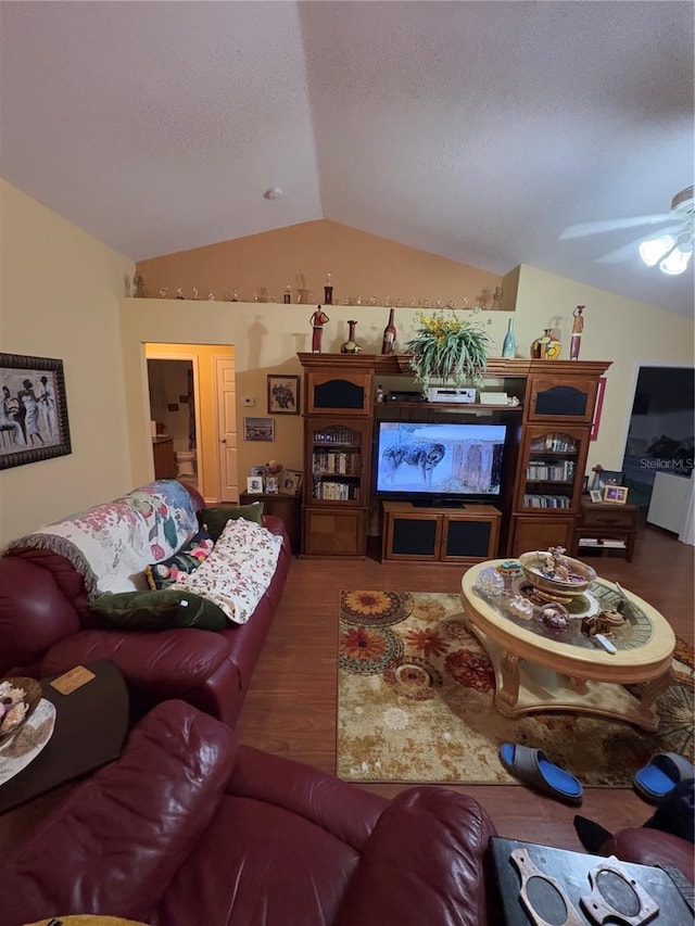 living room with ceiling fan, wood-type flooring, vaulted ceiling, and a textured ceiling