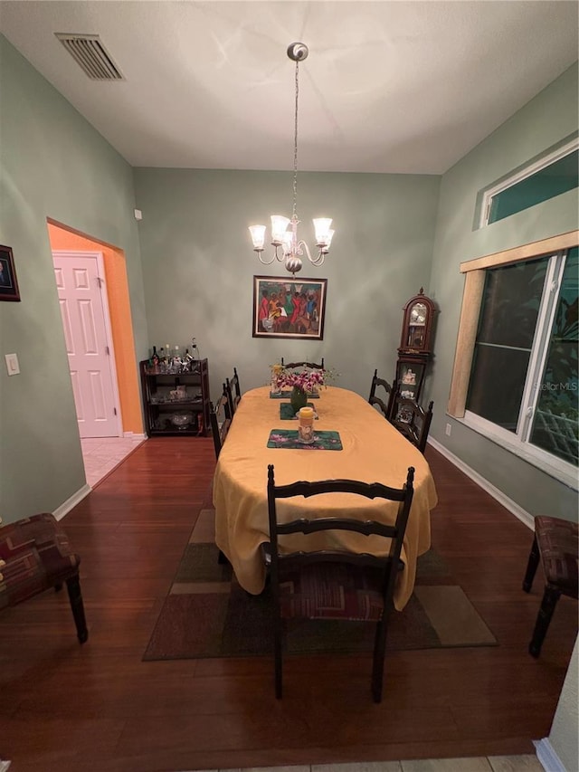 dining area with dark wood-type flooring and a notable chandelier