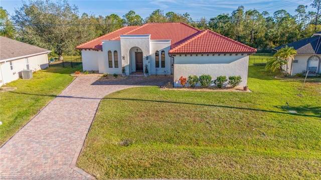 mediterranean / spanish house featuring a front lawn and central AC unit