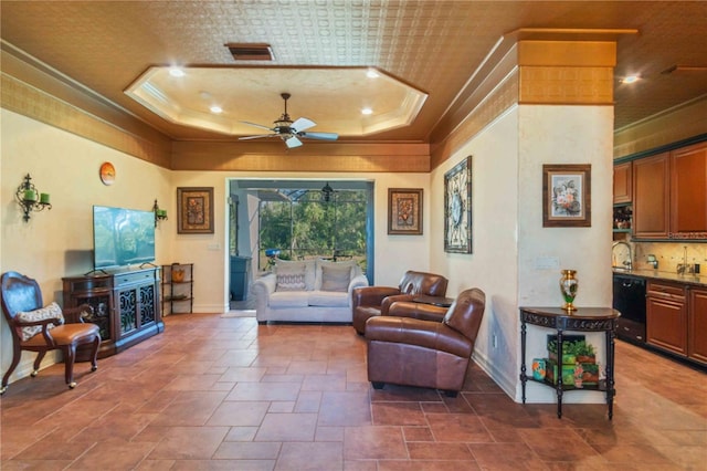 living room featuring a raised ceiling, ceiling fan, crown molding, and sink