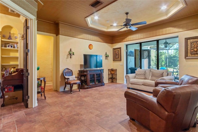 living room featuring ceiling fan, a raised ceiling, built in features, and ornamental molding