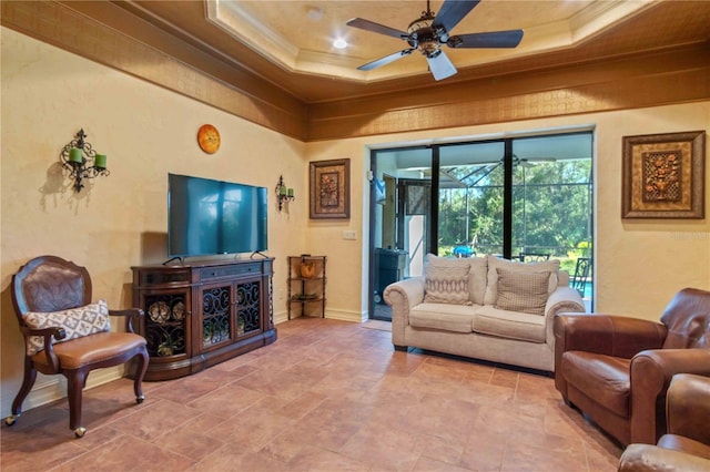 living room featuring ceiling fan, ornamental molding, and a tray ceiling