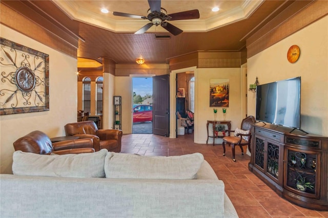 living room with a tray ceiling, crown molding, and ceiling fan