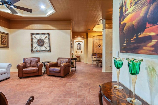 living room with a tray ceiling, ceiling fan, and crown molding