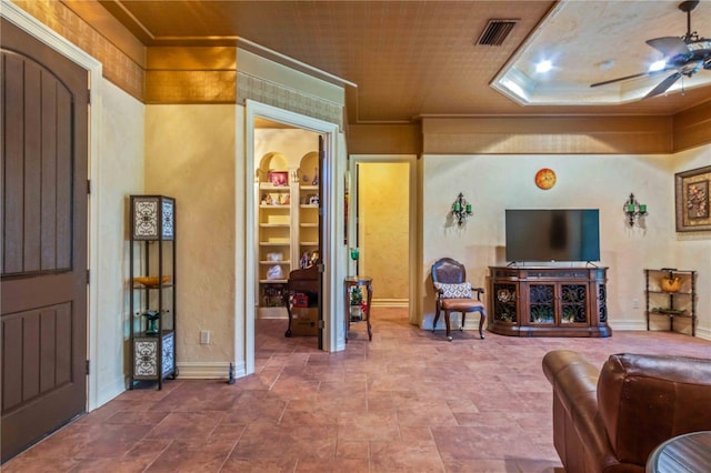 living room with ceiling fan, built in features, and ornamental molding