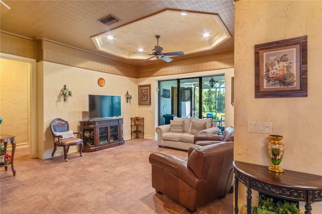 living room featuring a tray ceiling, ceiling fan, and ornamental molding