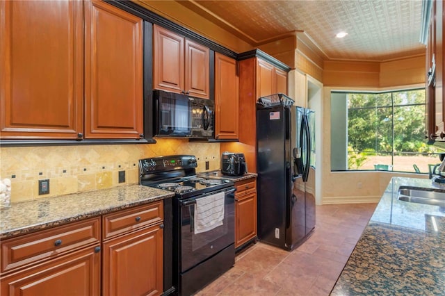 kitchen featuring black appliances, stone countertops, and sink