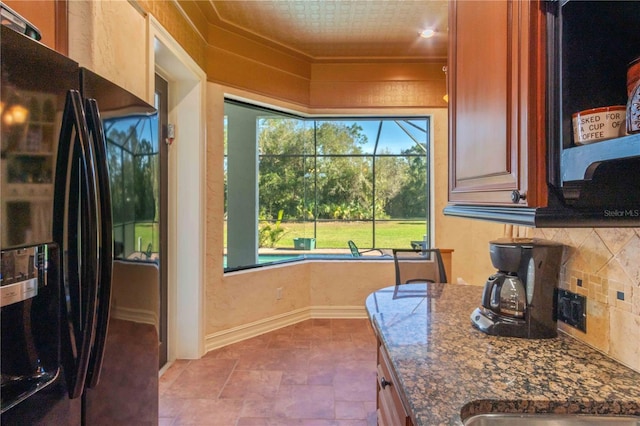 kitchen featuring tasteful backsplash, a wealth of natural light, black fridge, and dark stone countertops