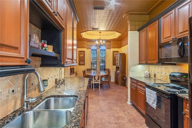 kitchen with sink, an inviting chandelier, dark stone counters, decorative light fixtures, and black appliances