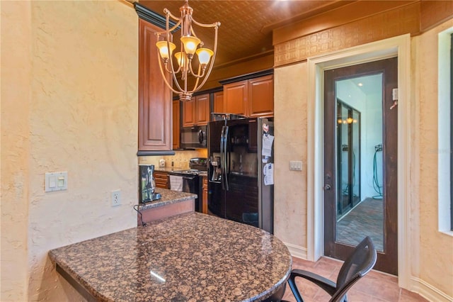 kitchen featuring black appliances, a kitchen breakfast bar, hanging light fixtures, dark stone countertops, and a chandelier