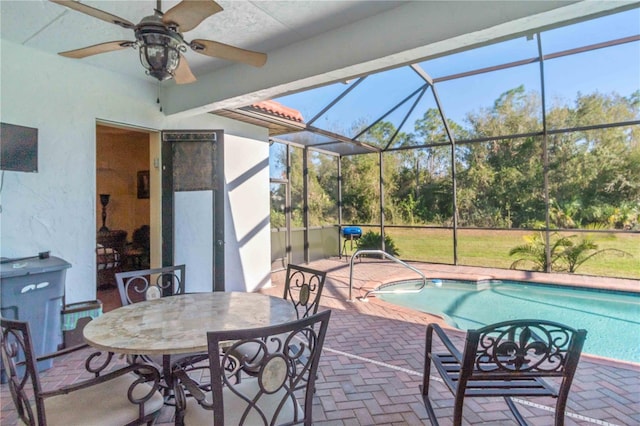 view of swimming pool with glass enclosure, ceiling fan, and a patio area