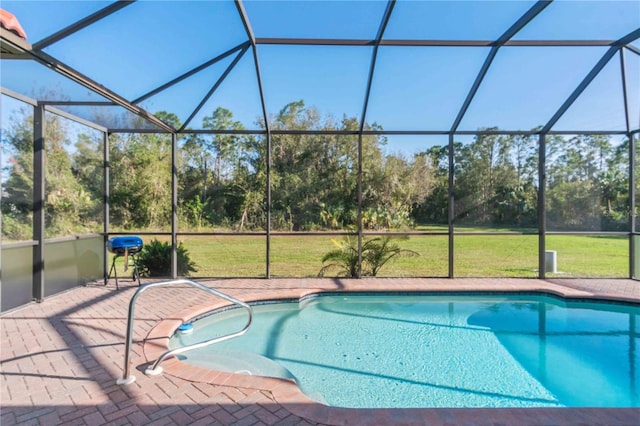 view of swimming pool with a yard, glass enclosure, and a patio area