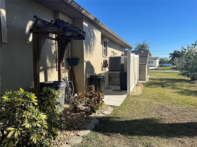 view of side of property with central AC unit and a yard