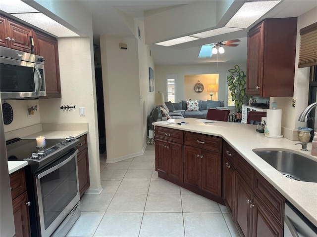 kitchen featuring sink, ceiling fan, appliances with stainless steel finishes, light tile patterned flooring, and kitchen peninsula