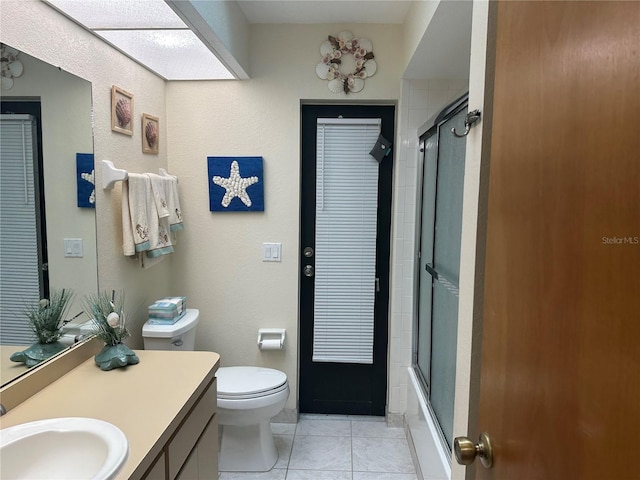 full bathroom featuring toilet, tile patterned floors, bath / shower combo with glass door, and vanity