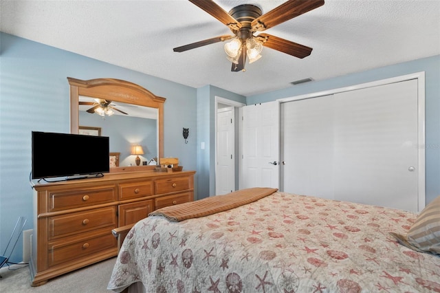 carpeted bedroom featuring ceiling fan and a textured ceiling