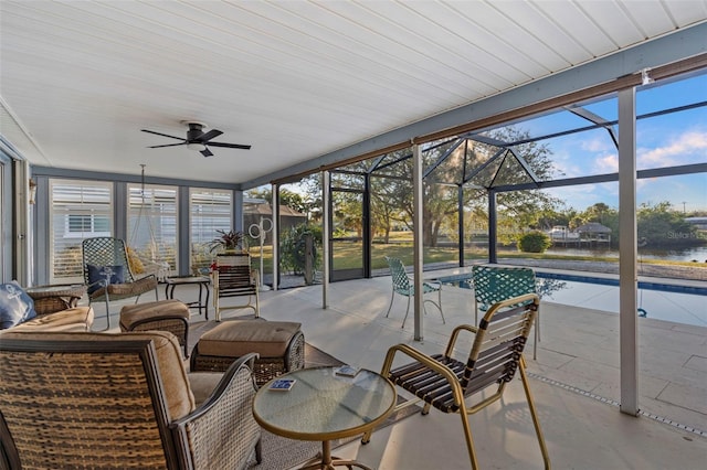 sunroom featuring ceiling fan, a healthy amount of sunlight, and a water view