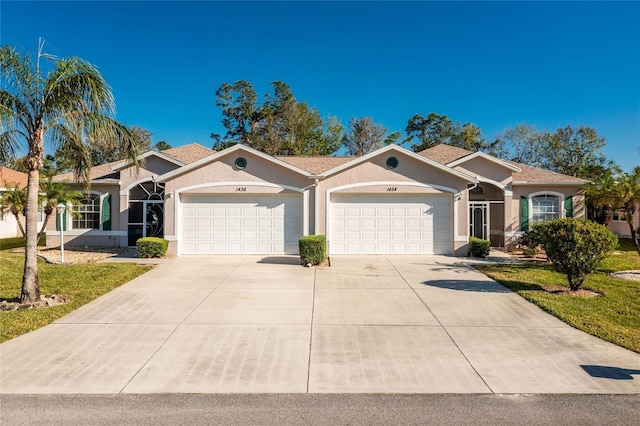 ranch-style house with concrete driveway, a front lawn, an attached garage, and stucco siding