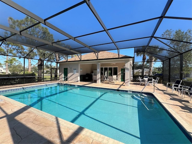 pool with glass enclosure, a ceiling fan, and a patio