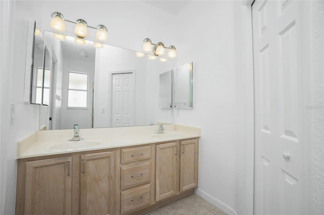 full bath with double vanity, baseboards, a sink, and tile patterned floors