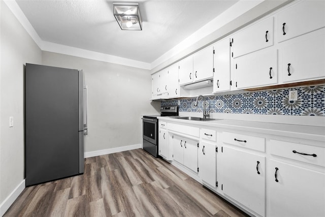 kitchen with sink, white cabinetry, stainless steel appliances, light hardwood / wood-style floors, and decorative backsplash