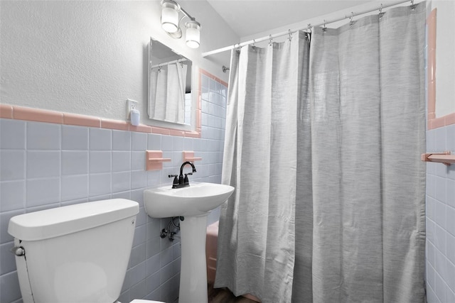 bathroom featuring curtained shower, toilet, and tile walls