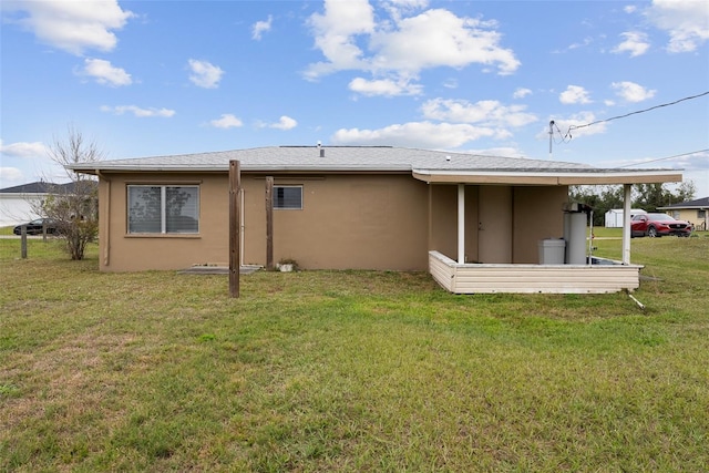 rear view of property with a lawn and stucco siding