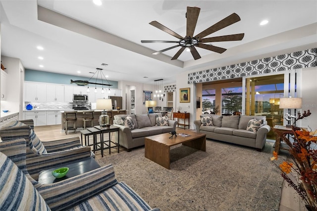 living room with ceiling fan and a raised ceiling