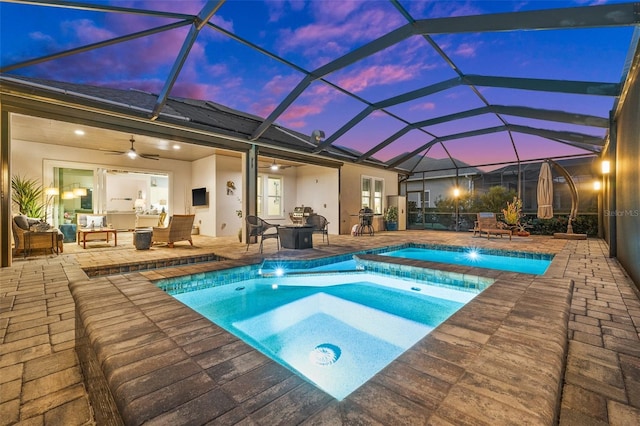 view of swimming pool featuring an in ground hot tub, glass enclosure, an outdoor living space with a fire pit, and a patio area