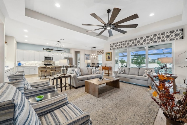 living room with a raised ceiling and ceiling fan