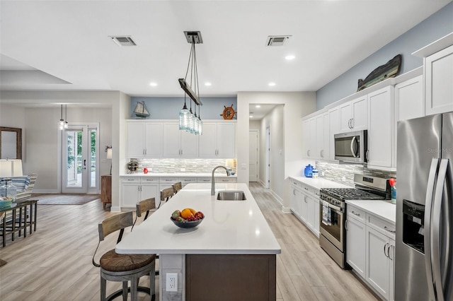 kitchen featuring sink, white cabinetry, stainless steel appliances, and hanging light fixtures