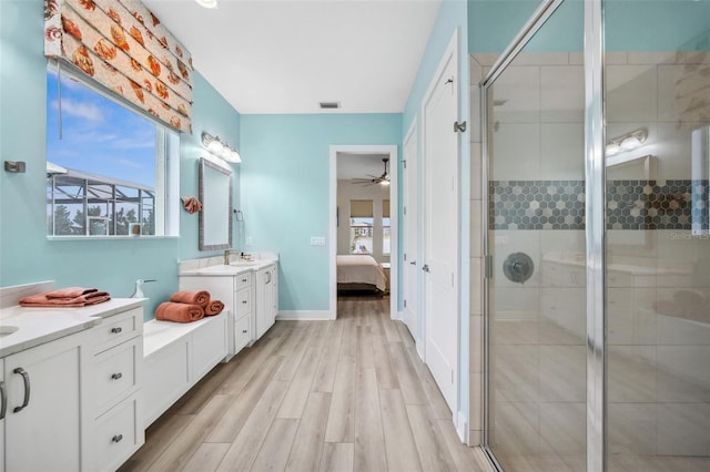 bathroom with ceiling fan, vanity, a shower with shower door, and wood-type flooring