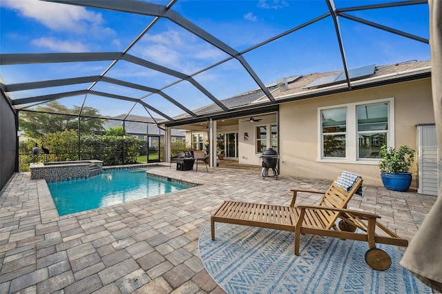 view of swimming pool with glass enclosure, ceiling fan, an in ground hot tub, a grill, and a patio area