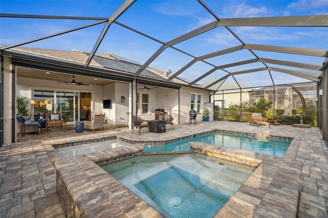 view of swimming pool with glass enclosure, an in ground hot tub, a patio, and an outdoor fire pit