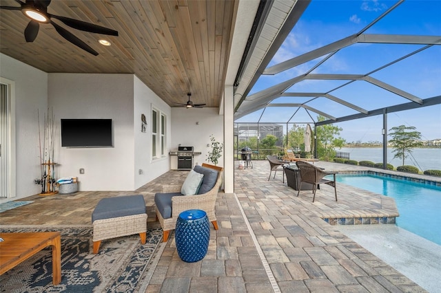 view of patio / terrace with an outdoor living space, ceiling fan, a water view, glass enclosure, and grilling area