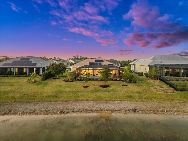 view of front of house featuring glass enclosure, a yard, and solar panels