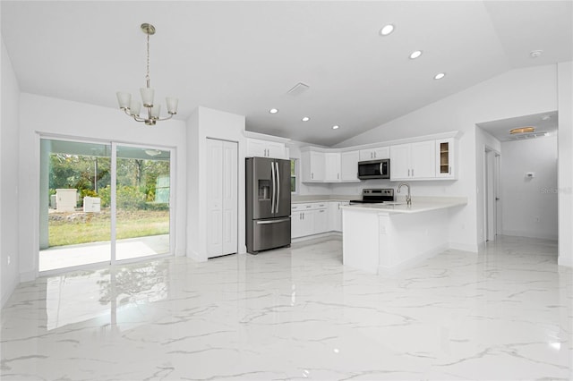 kitchen featuring kitchen peninsula, stainless steel appliances, lofted ceiling, hanging light fixtures, and white cabinets