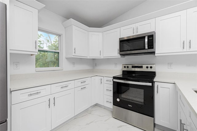 kitchen with white cabinetry, appliances with stainless steel finishes, and lofted ceiling