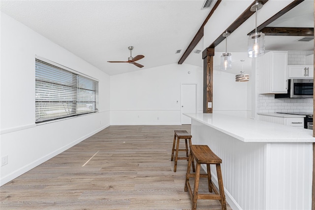 kitchen with tasteful backsplash, white cabinetry, a breakfast bar area, hanging light fixtures, and light hardwood / wood-style floors