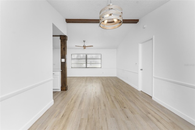 interior space featuring ceiling fan, light hardwood / wood-style floors, a textured ceiling, and vaulted ceiling with beams