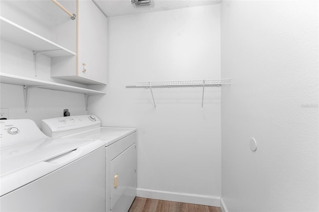 laundry room with cabinets, washer and dryer, and light hardwood / wood-style flooring